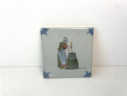 Makkum Tichelaar tegel uit de jaren 1960 met handgeschilderde voorstelling van poetsvrouw.