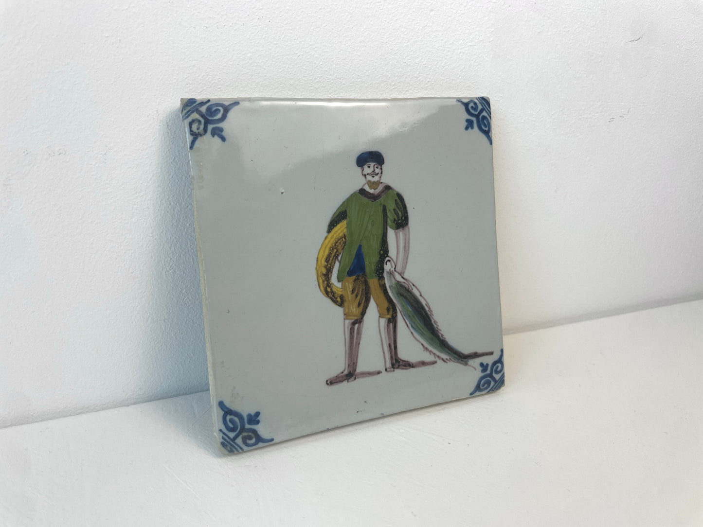 Antieke keramieken tegel van Makkum met tafereel van een visser, deel van Tegelberoepen-serie.