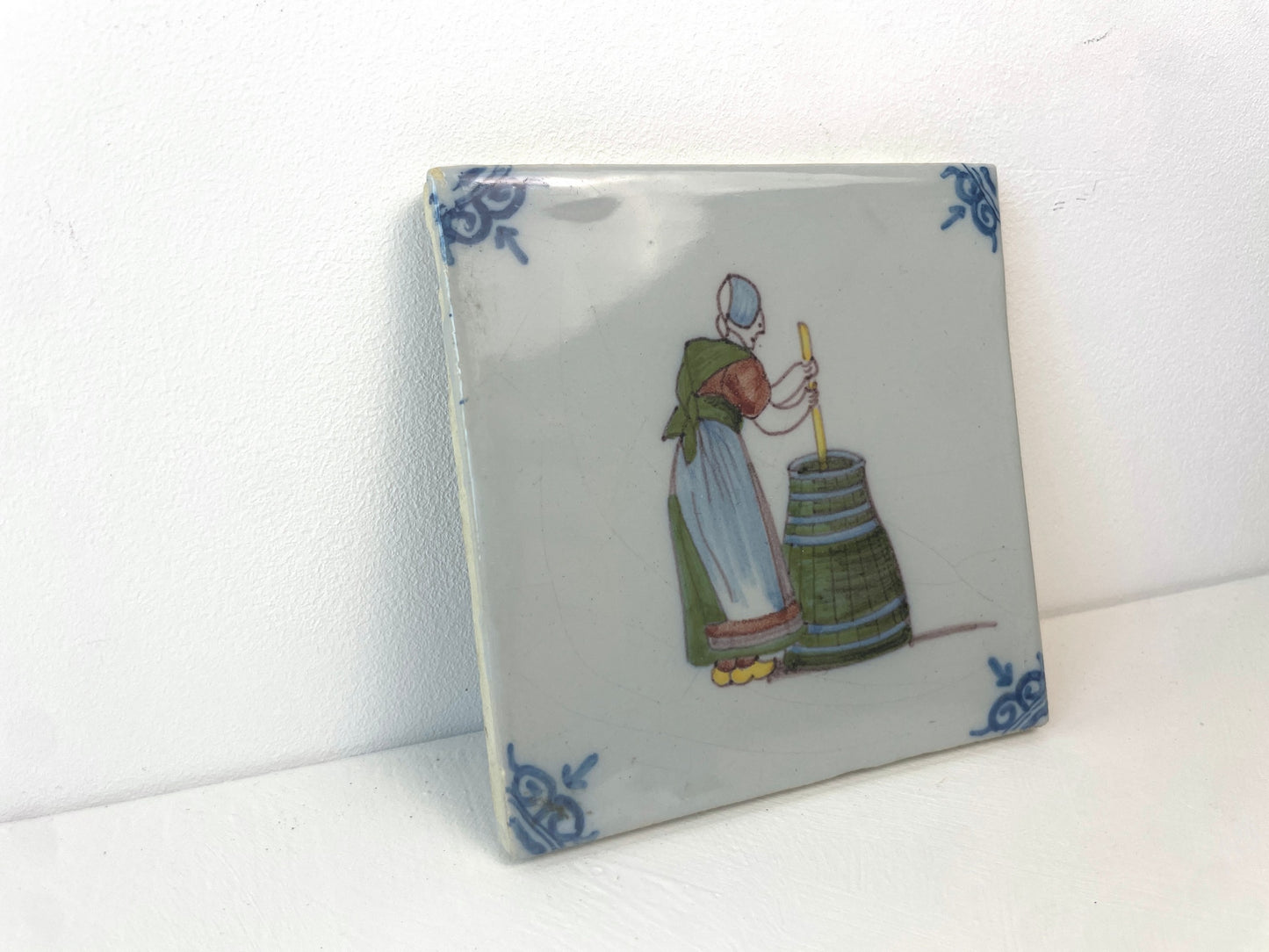 Antieke keramieken tegel van Makkum met tafereel uit de Tegelberoepen-serie.