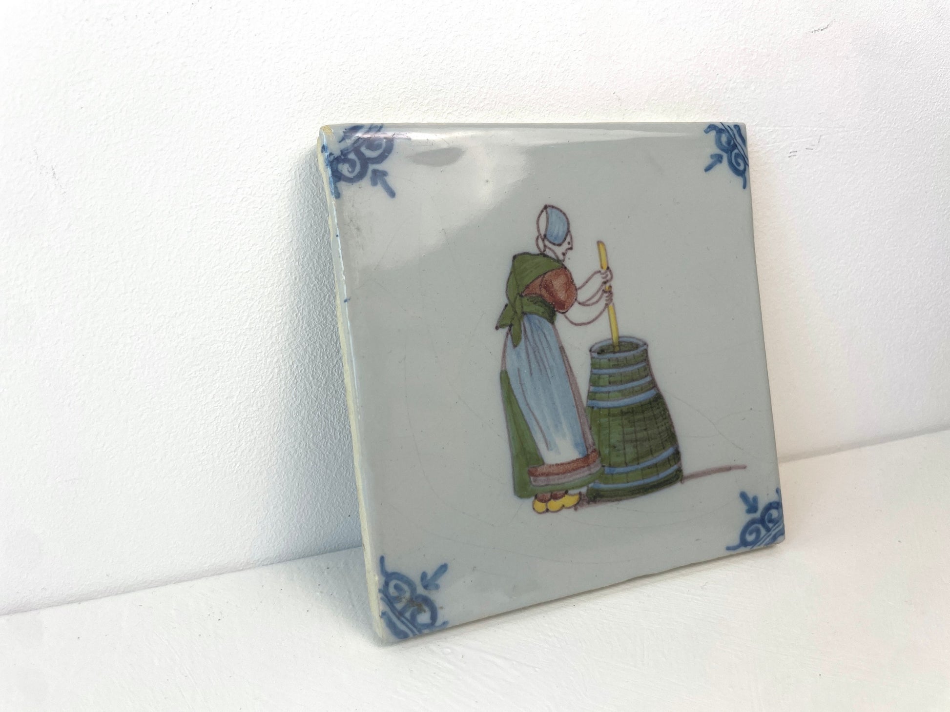 Antieke keramieken tegel van Makkum met tafereel uit de Tegelberoepen-serie.