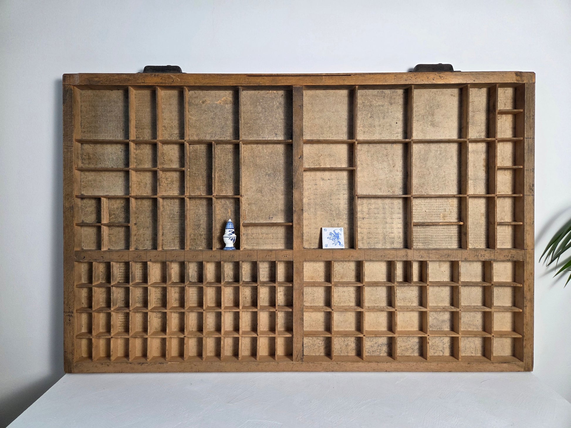 Oude drukkerijlade van hout met metalen handvatten, letterbak aan de muur.