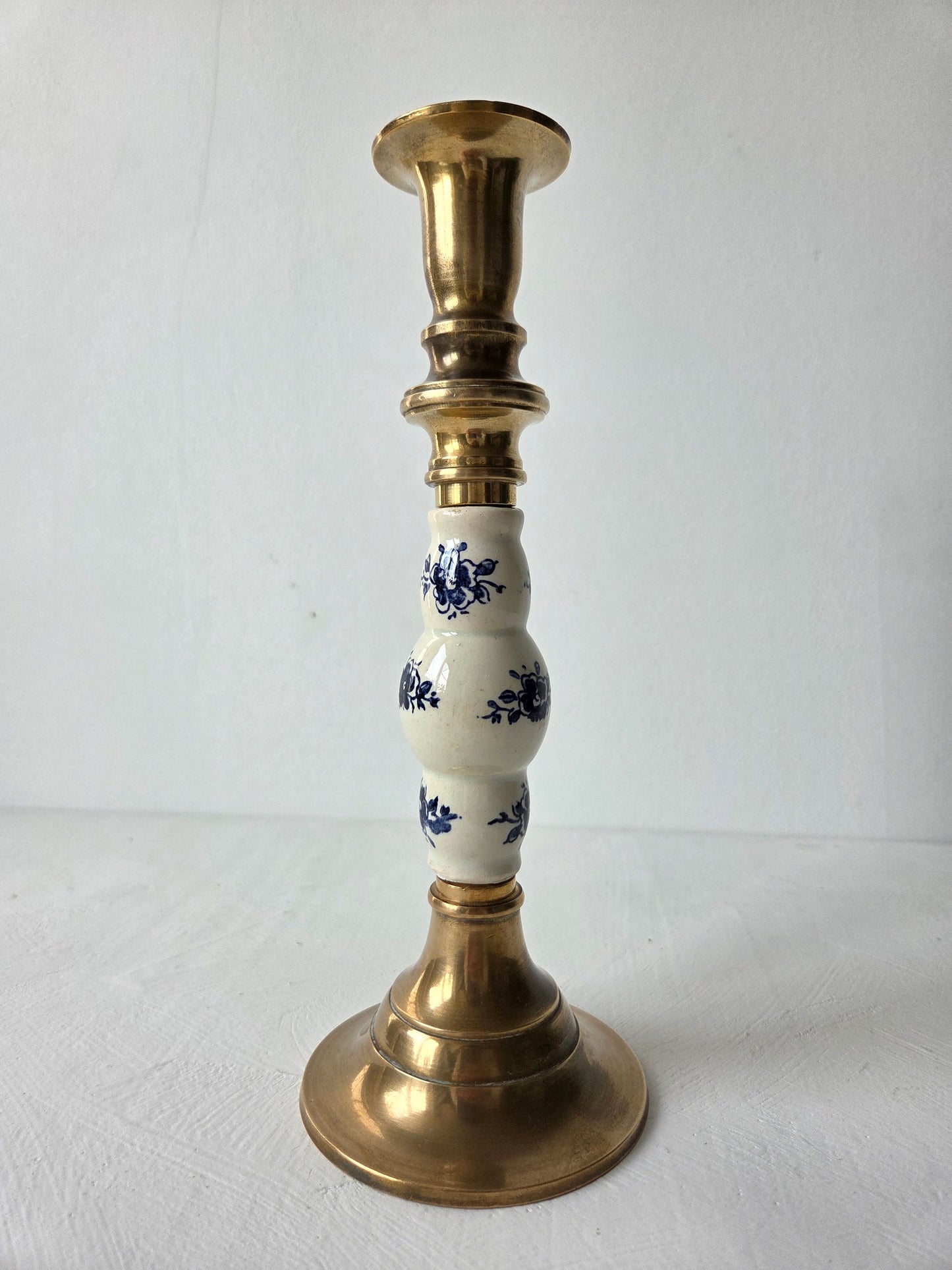 Vintage messing kandelaar met blauw-wit aardewerken tussenstuk op witte ondergrond