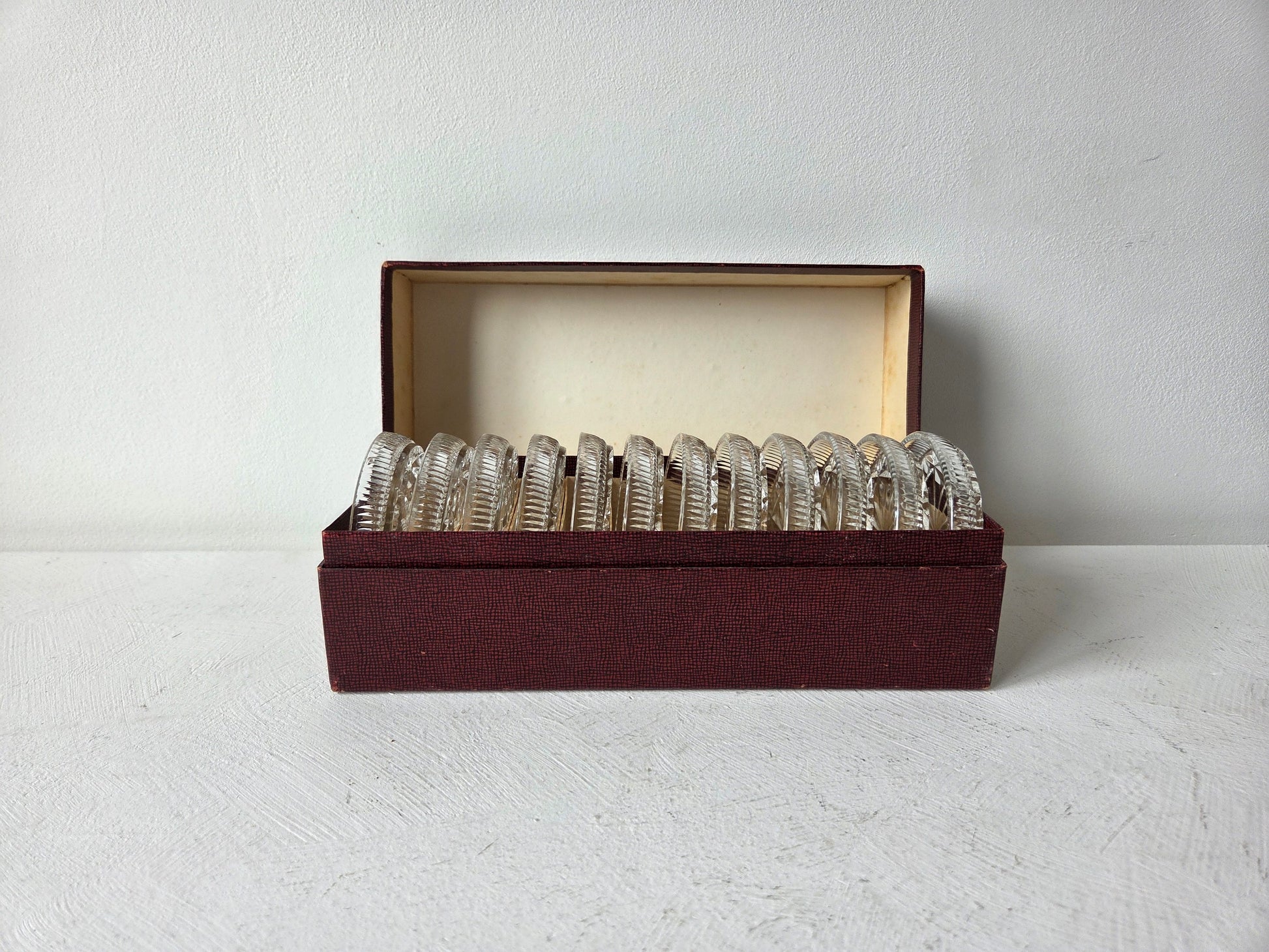 Twaalf glazen onderzetters in donkerrode bewaardoos – vintage tafelaccessoire bij D’Antan