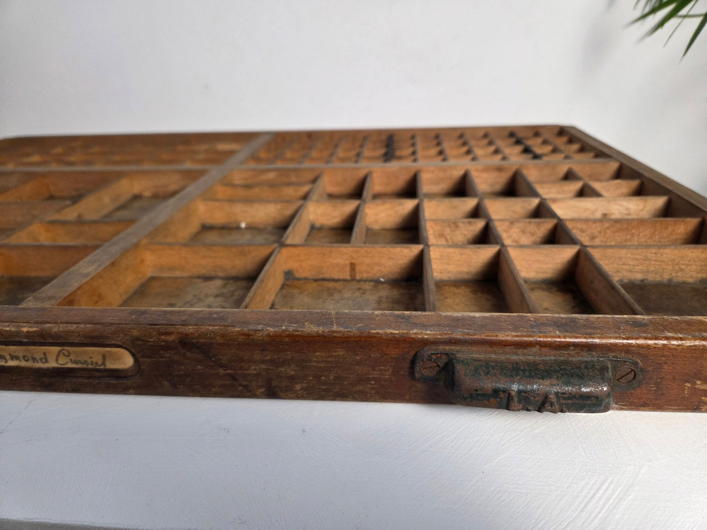 Vintage drukkerijlade van hout met metalen handvatten, gebruikt als wandrek