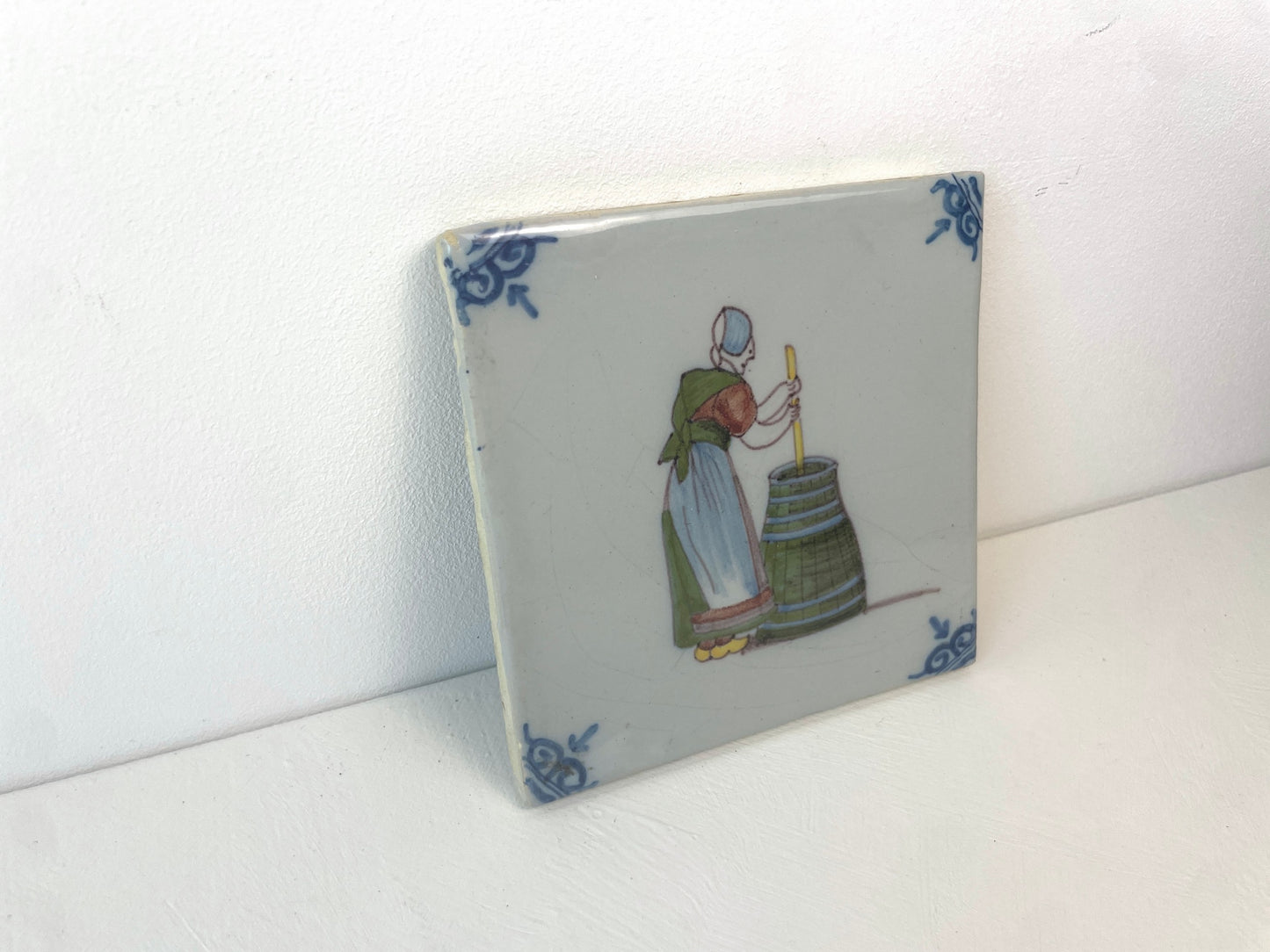 Antiek keramiek van Makkum, tegel met geschilderde voorstelling van poetsvrouw.