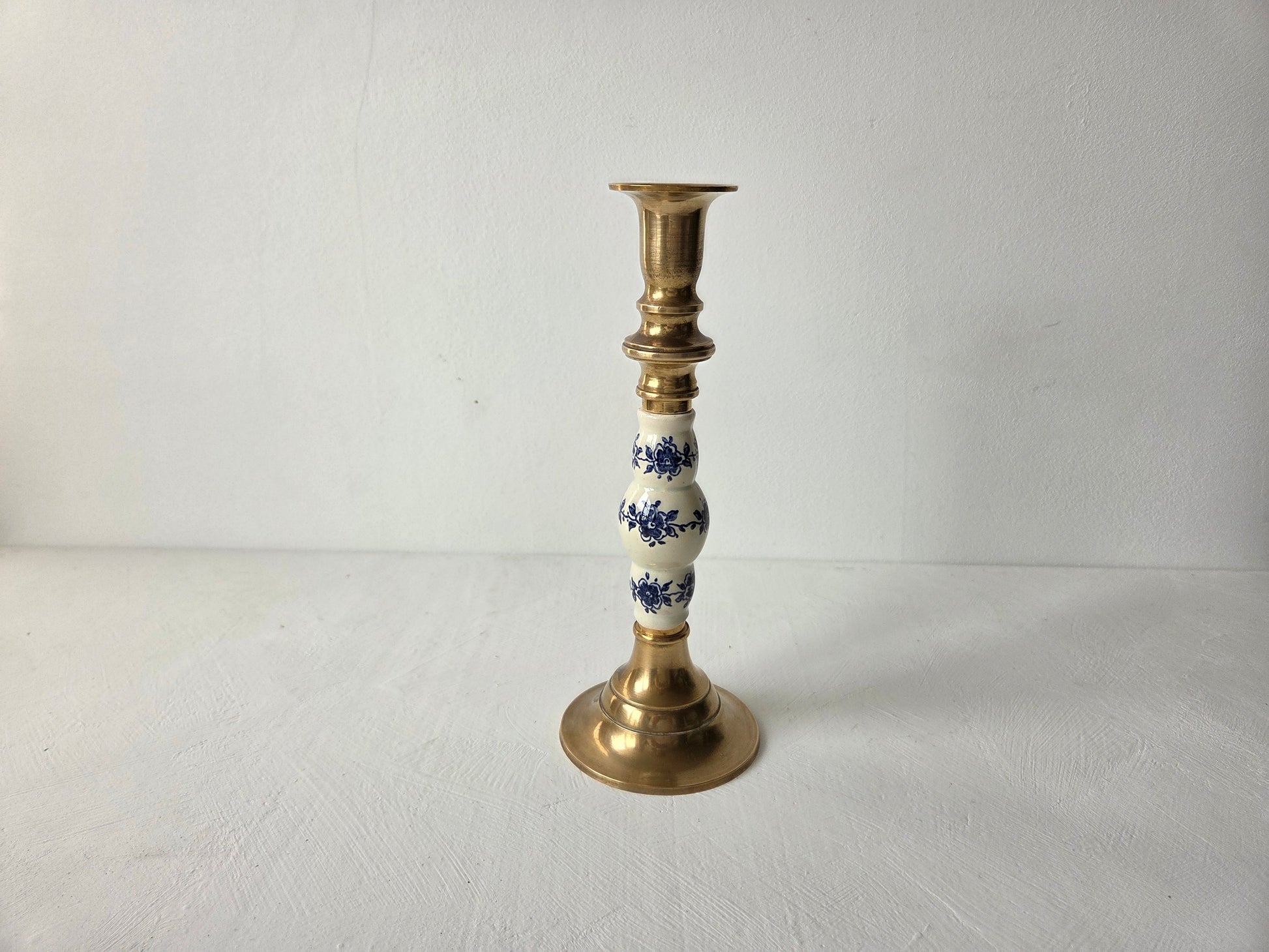 Messing kandelaar met ronde voet en blauw-wit bloemmotief op het aardewerk