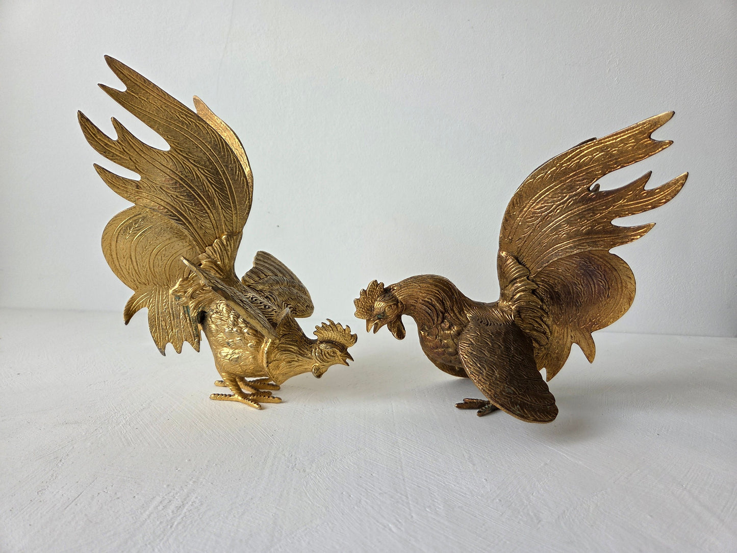 Goudkleurige metalen haanfiguren met sierlijke staarten en uitgespreide vleugels