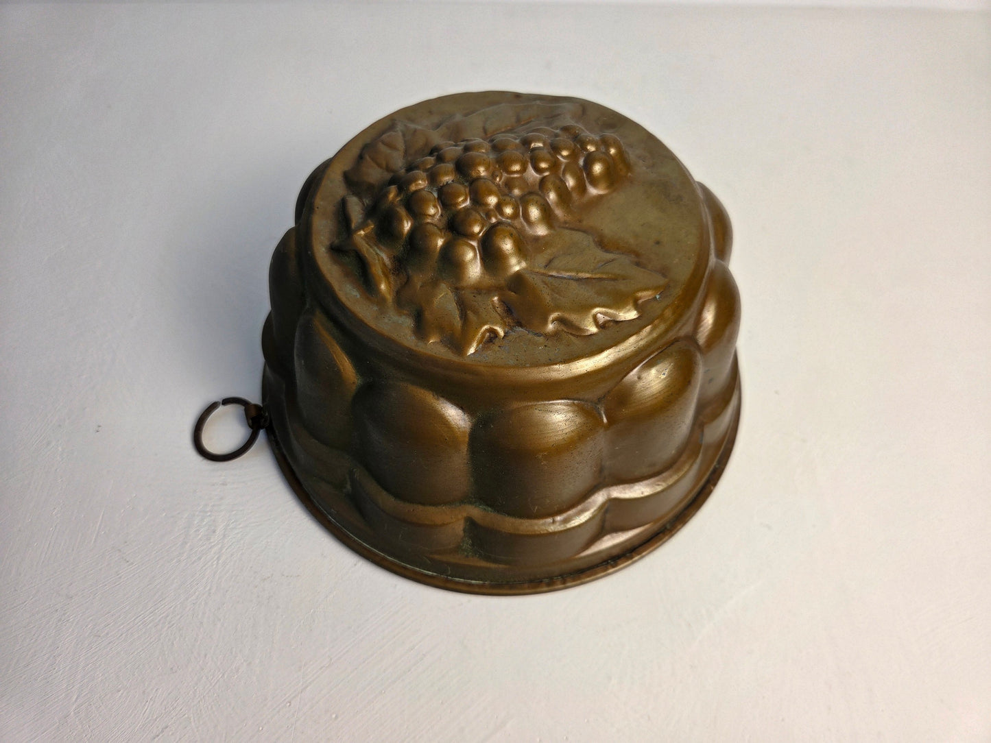 antieke koperen cakevorm met druivenpatroon