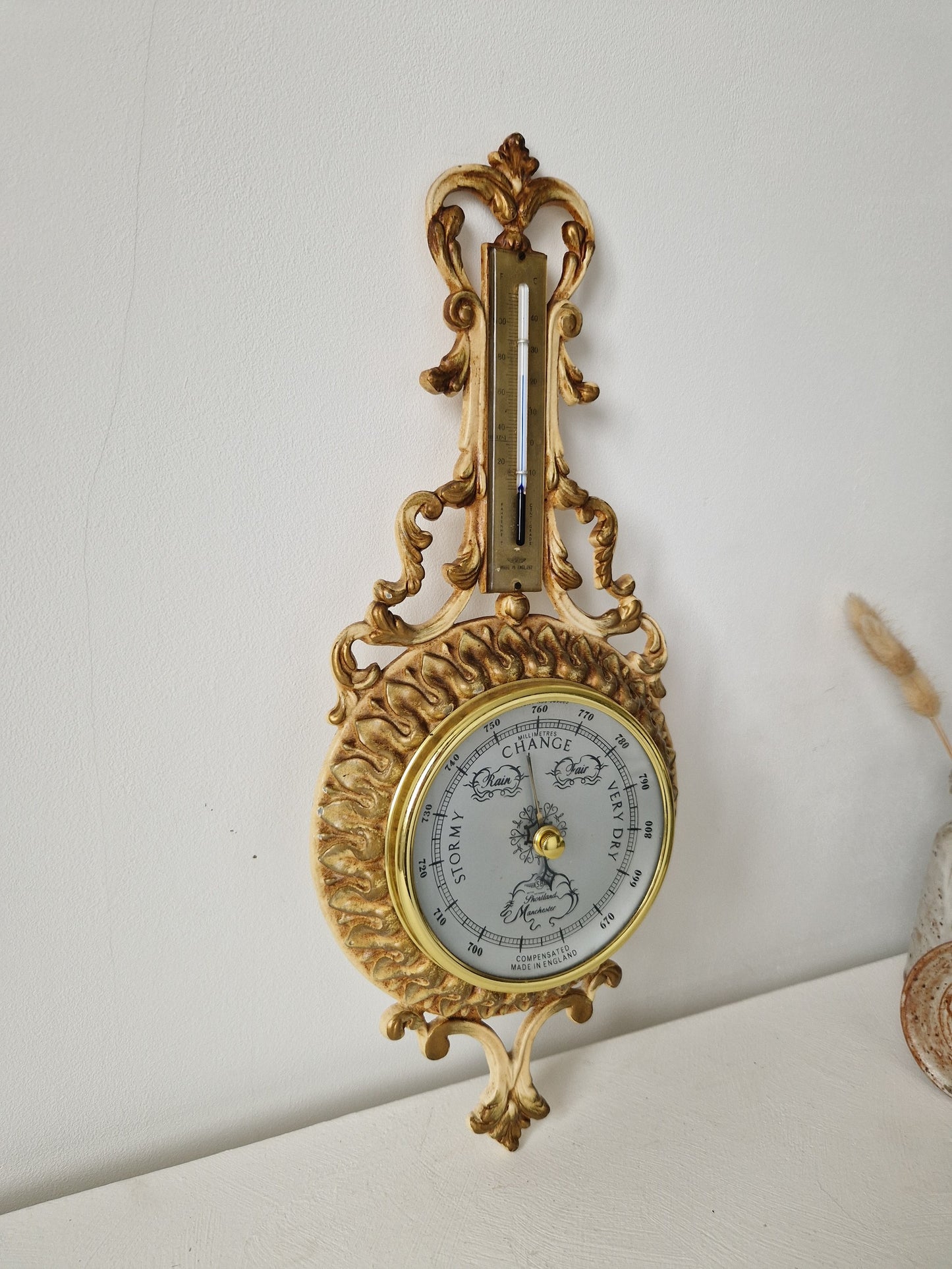 Goudkleurige wandbarometer met witte schaal