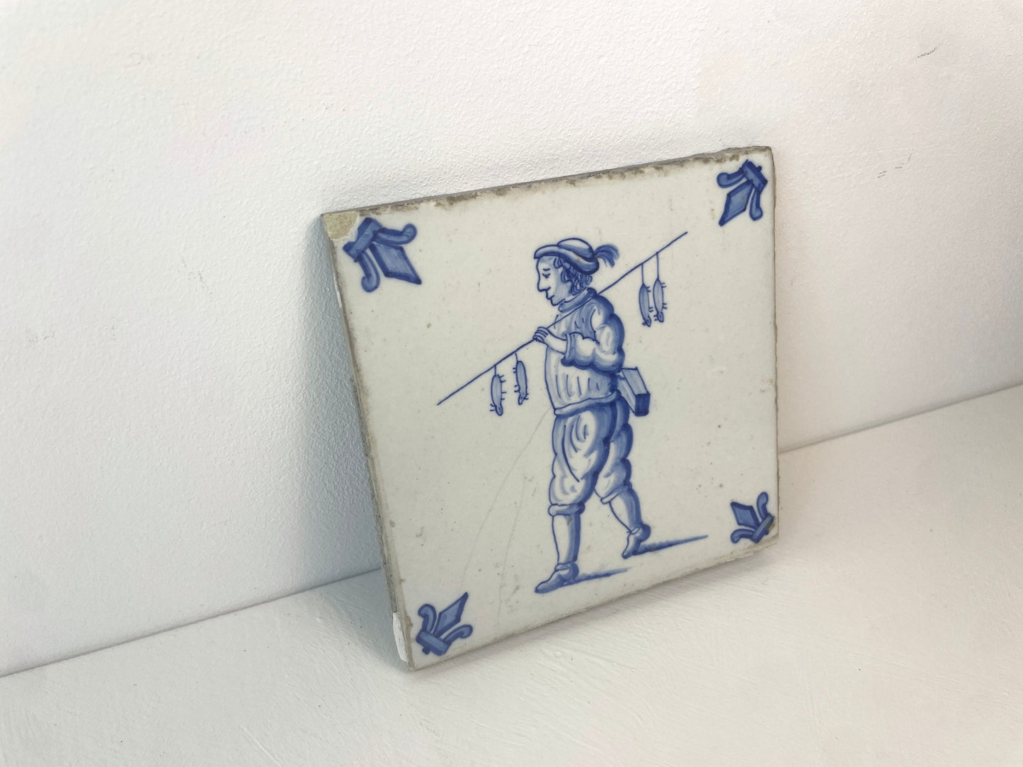 Antieke tegel met figuur en ratten aan draagstok