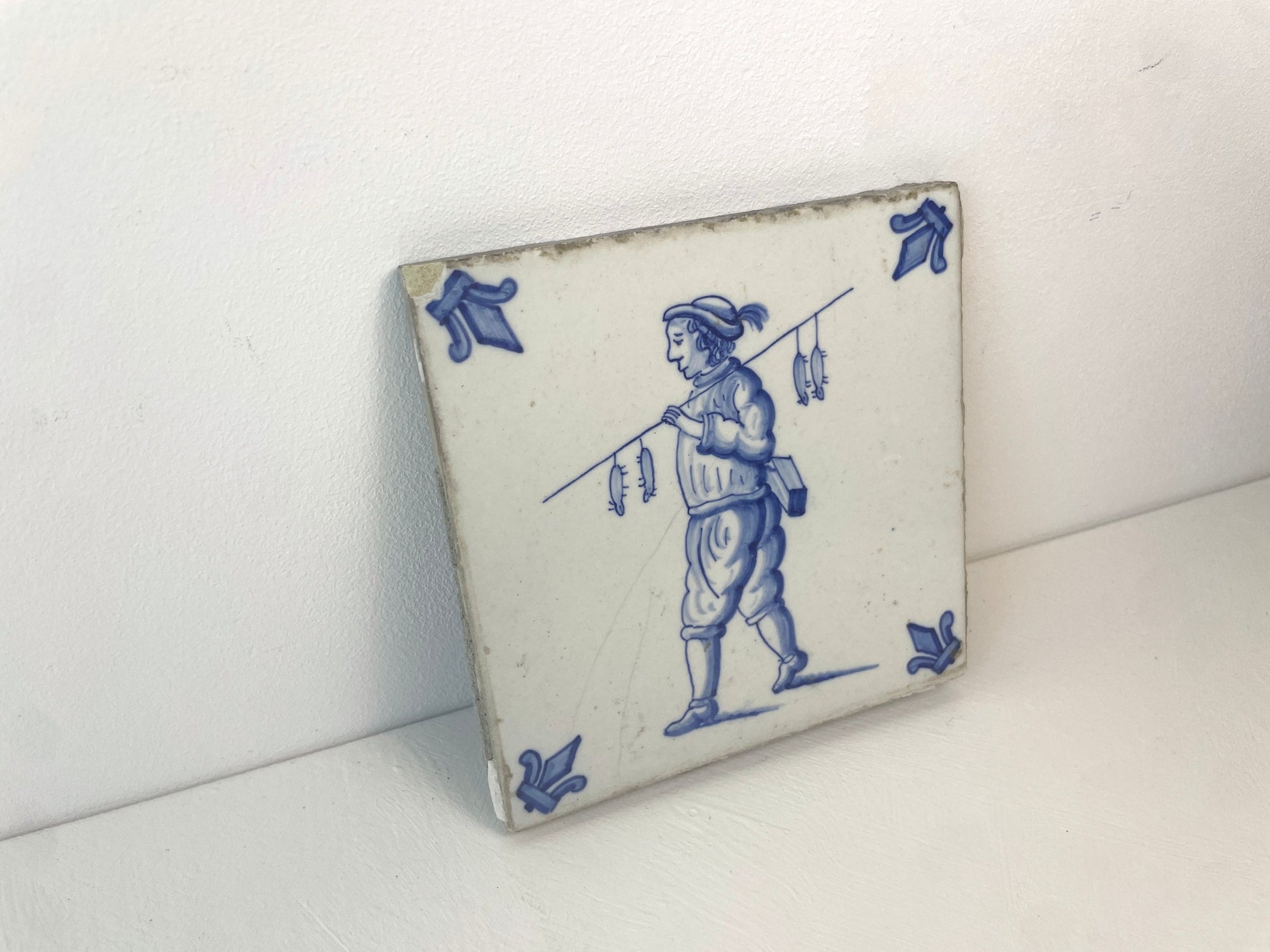 Antieke tegel met figuur en ratten aan draagstok