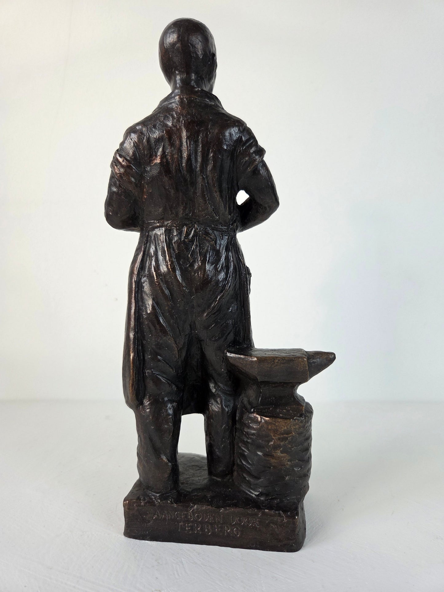 Donkerkleurig metalen smid beeld op voet